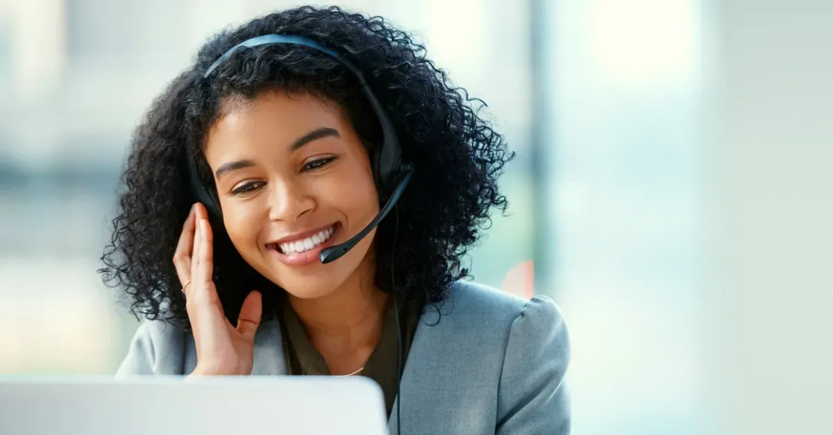 Smiling  woman with headset working on laptop in office.