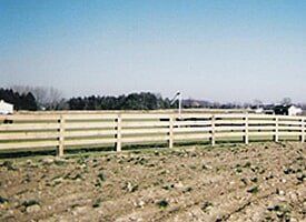 There is a wooden fence in the middle of a field.