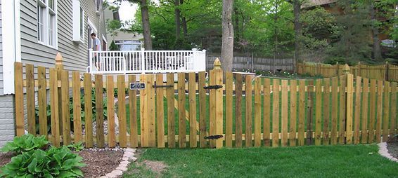 A wooden picket fence is in the backyard of a house. A wooden picket fence is in the backyard of a house.