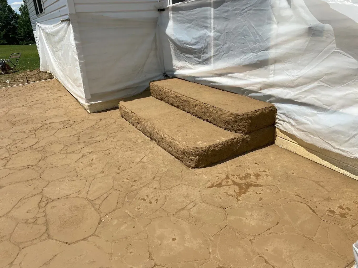 Two straw steps leading to a white tent on cracked dirt ground