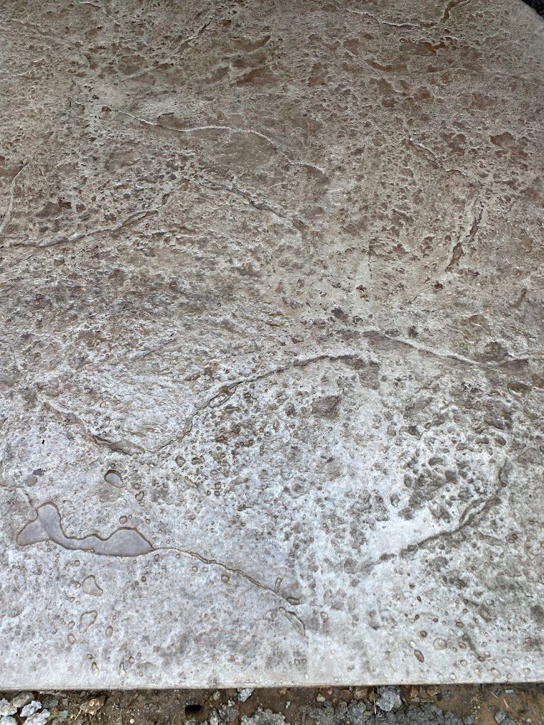 Close-up of a beige, textured stone or tile surface with faint circular marks