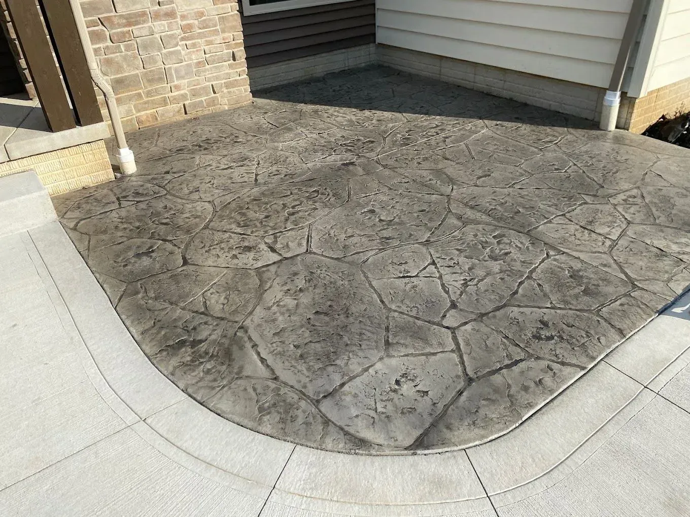 Stamped concrete patio with a curved edge beside a house entrance