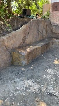 Rough stone steps built into a landscaped hillside beside a brick wall and trees
