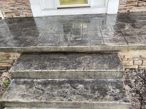 Stone front steps and landing leading to a white door, wet with dark stains and weathering