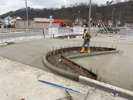 Worker smoothing concrete at a curb cut in a construction site