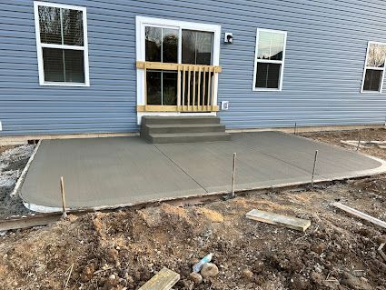 Concrete front porch with temporary wooden railing at a blue house under construction