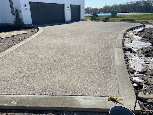 Concrete driveway beside garage, with patchy snow along the curb and a small toy truck near the edge