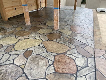 Stone-patterned floor under construction with exposed wooden posts and blue tape markings