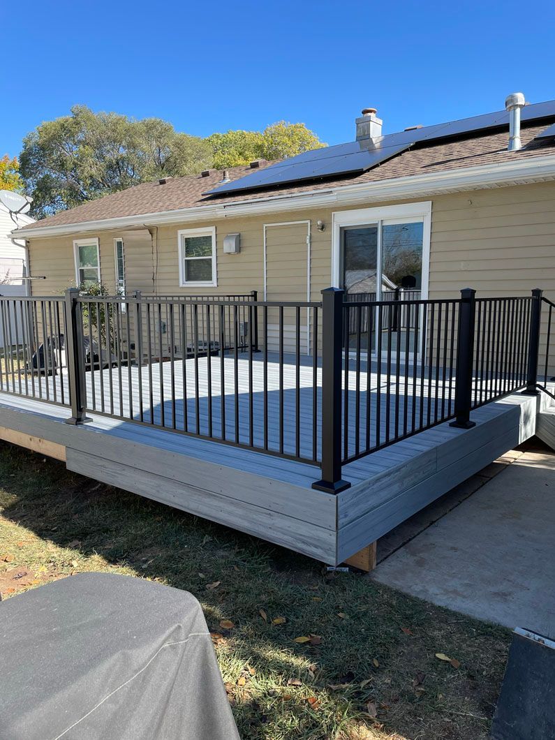 A large deck with a metal railing in front of a house.