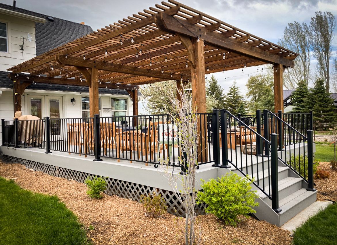 A deck with a pergola and stairs in front of a house.