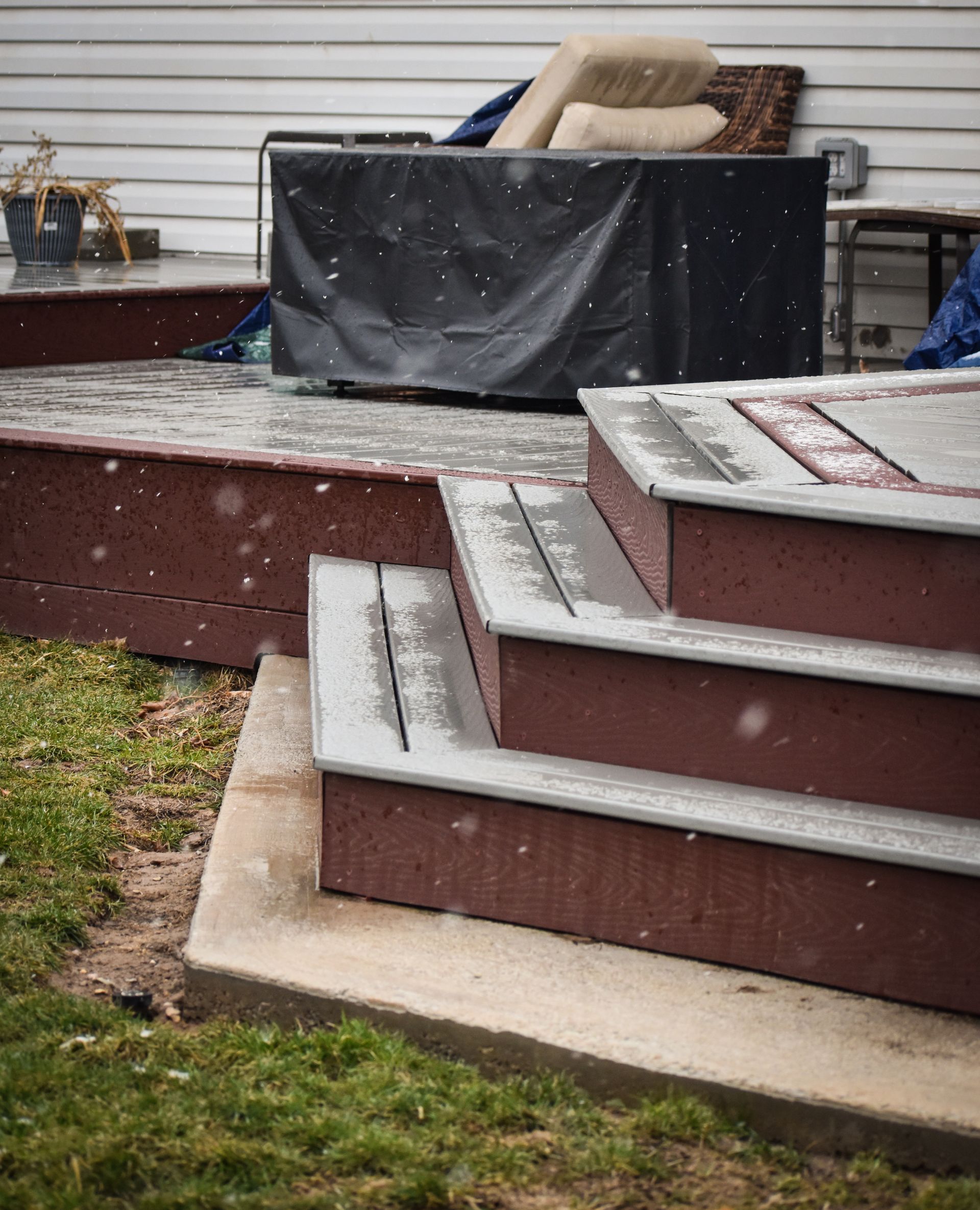 A deck with stairs leading up to it and a couch in the background.