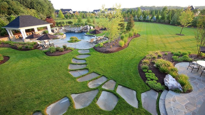 Backyard with lawn, outdoor bar, and seating area under a colorful sky.