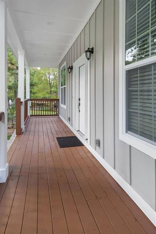 A long wooden porch leading to a house with white siding and windows.