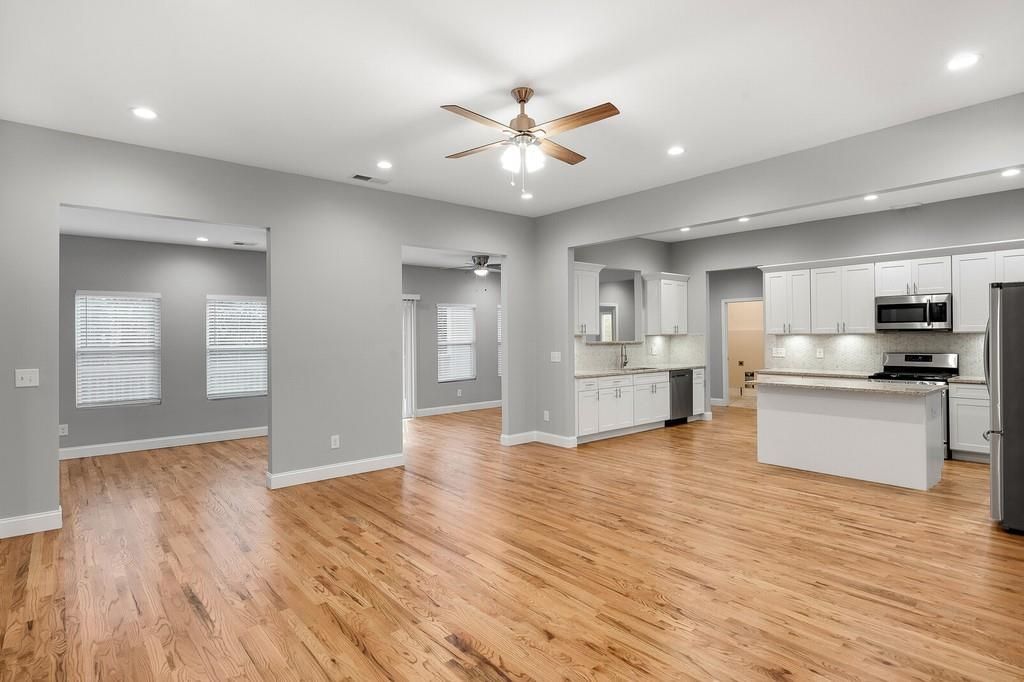 A large empty room with hardwood floors and a ceiling fan.