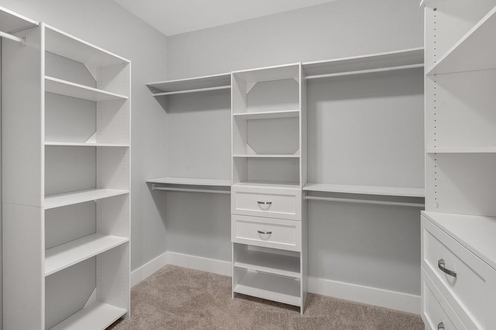 A walk in closet with lots of shelves and drawers.