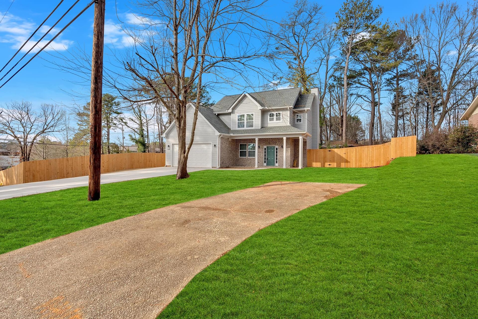 A house is sitting on top of a lush green lawn next to a gravel driveway.
