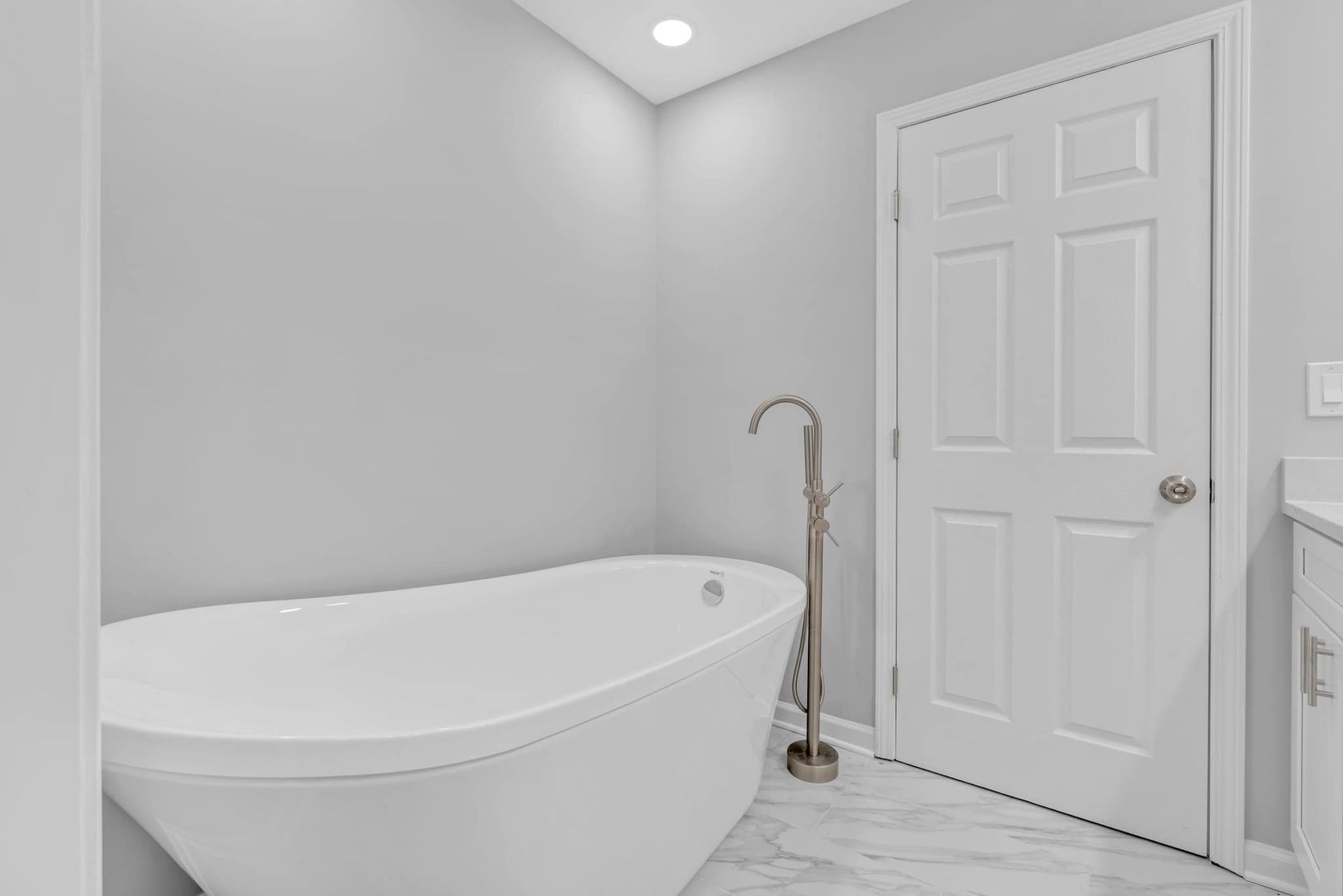 A bathroom with a bathtub , sink , and door.