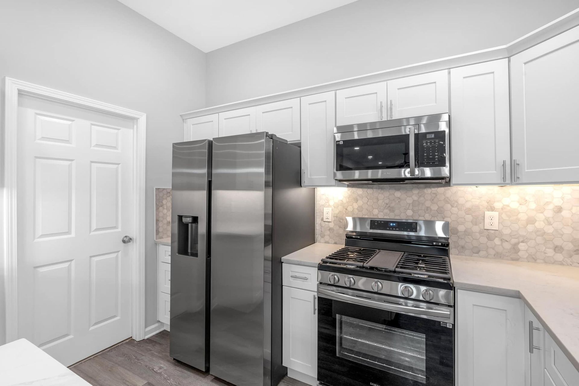 A kitchen with stainless steel appliances and white cabinets.