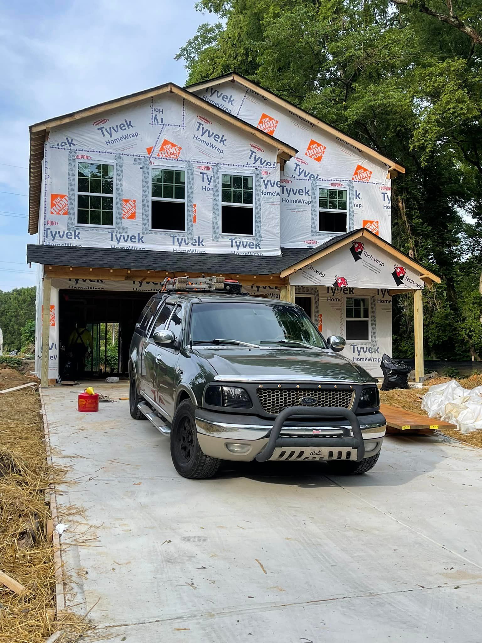 A car is parked in front of a house under construction.