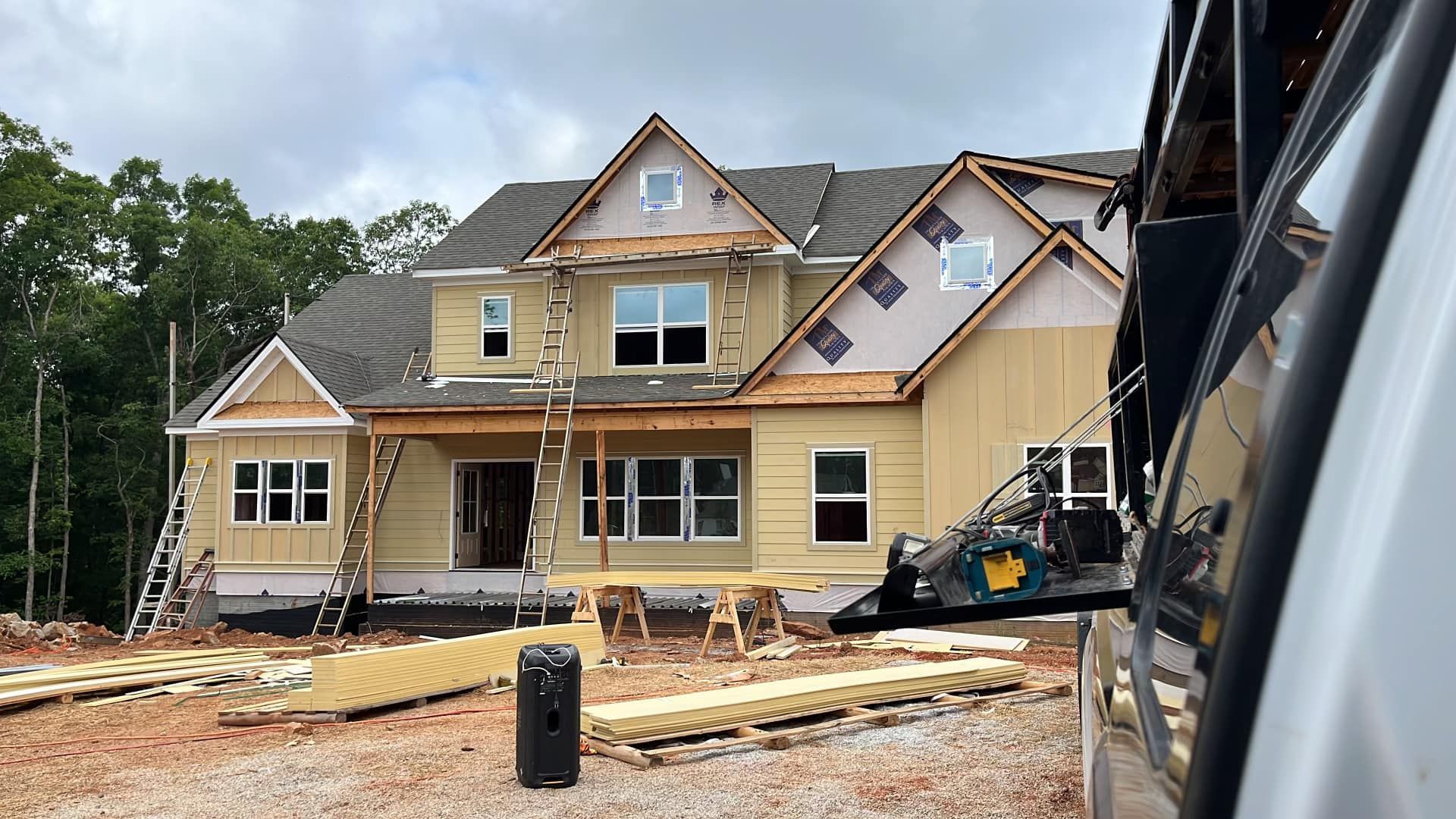 A large house is being built in the middle of a dirt field.