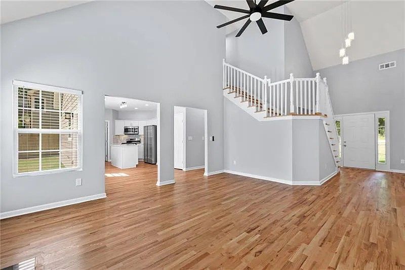 An empty living room with hardwood floors and a ceiling fan.