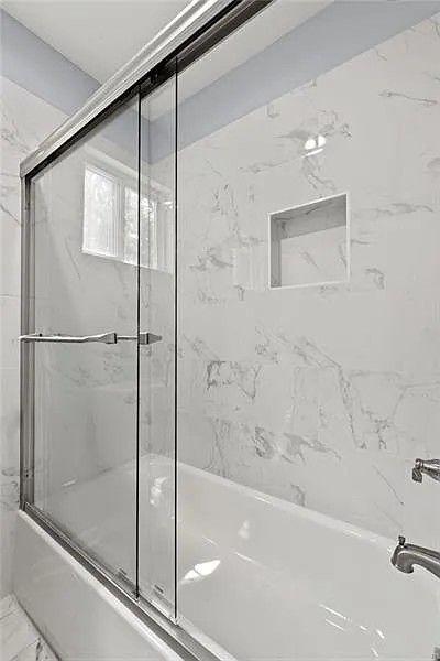 A bathroom with a bathtub and a sliding glass shower door.