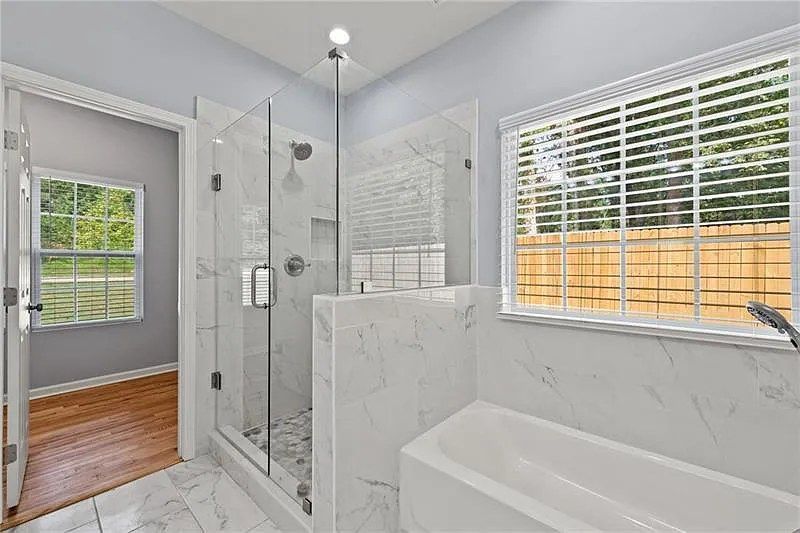 A bathroom with a tub , shower , and window.