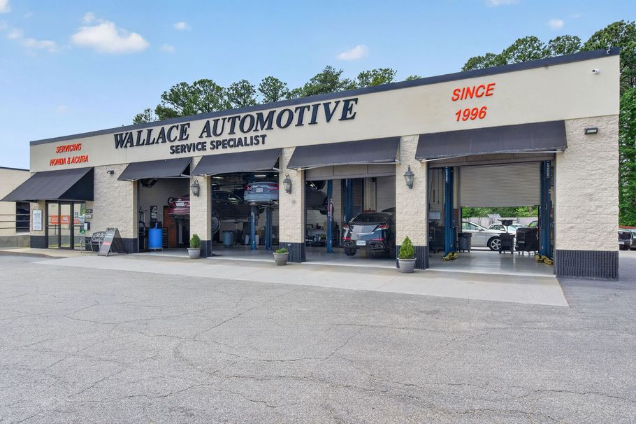 Technician at work in our garage looking under car lifted up | Wallace Automotive Inc