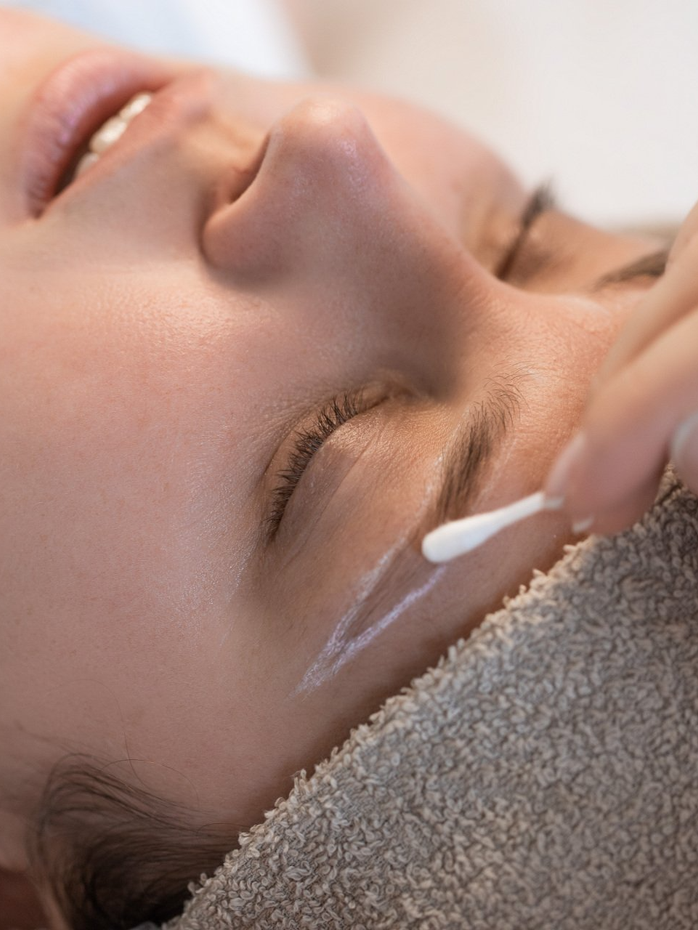 A woman is getting a facial treatment with a cotton swab.