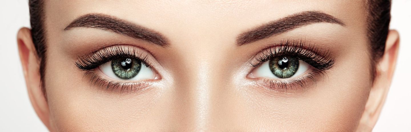 A close up of a woman 's green eyes with makeup.