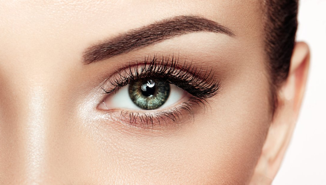 A close up of a woman 's green eye with makeup.