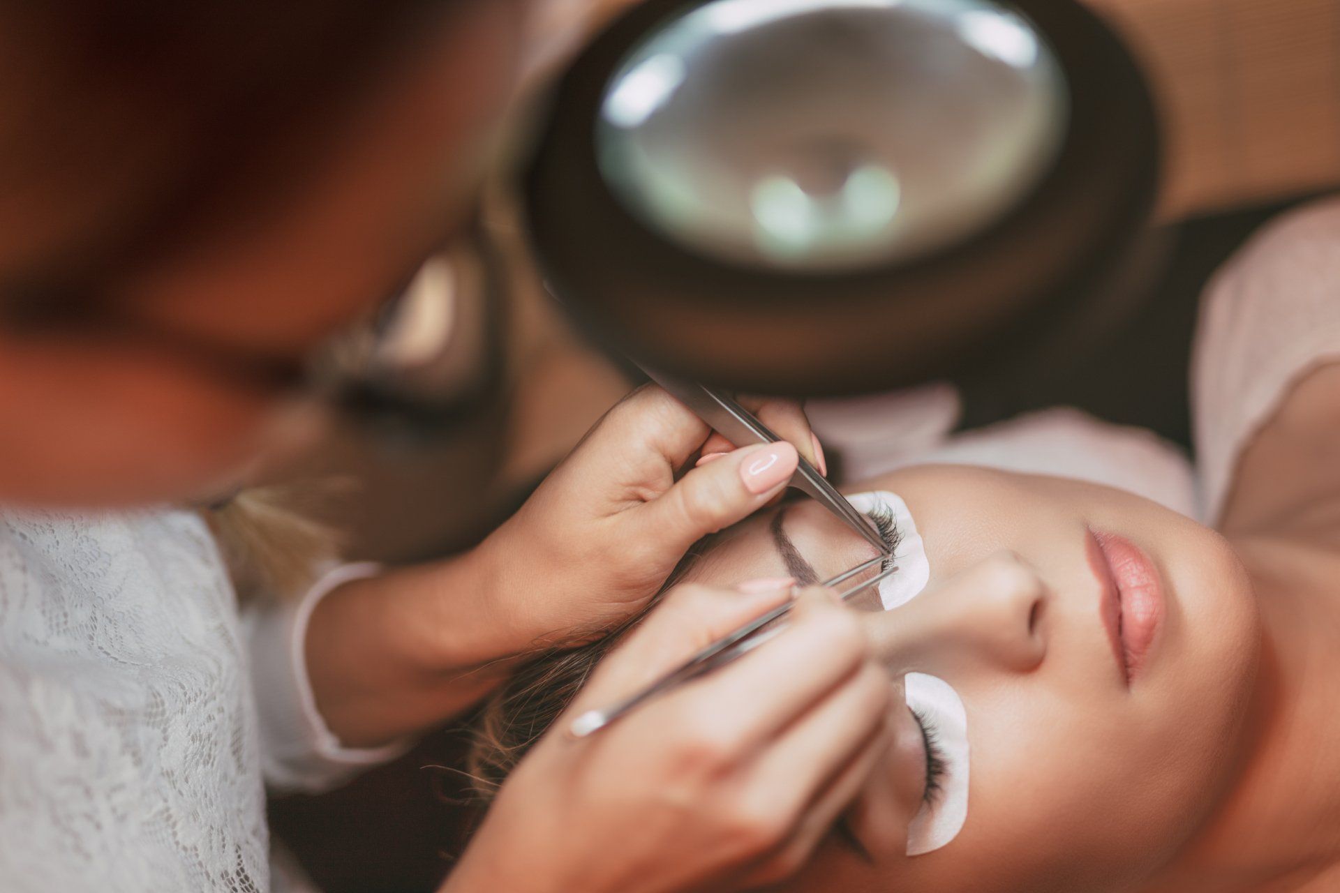 A woman is getting her eyelashes done by a makeup artist.