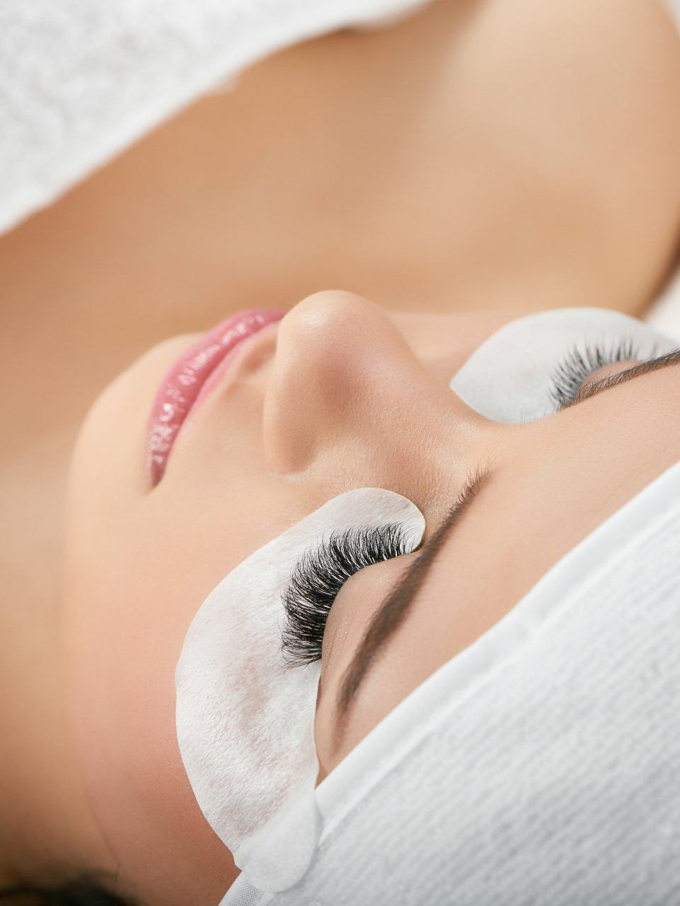A woman is getting eyelash extensions in a beauty salon.