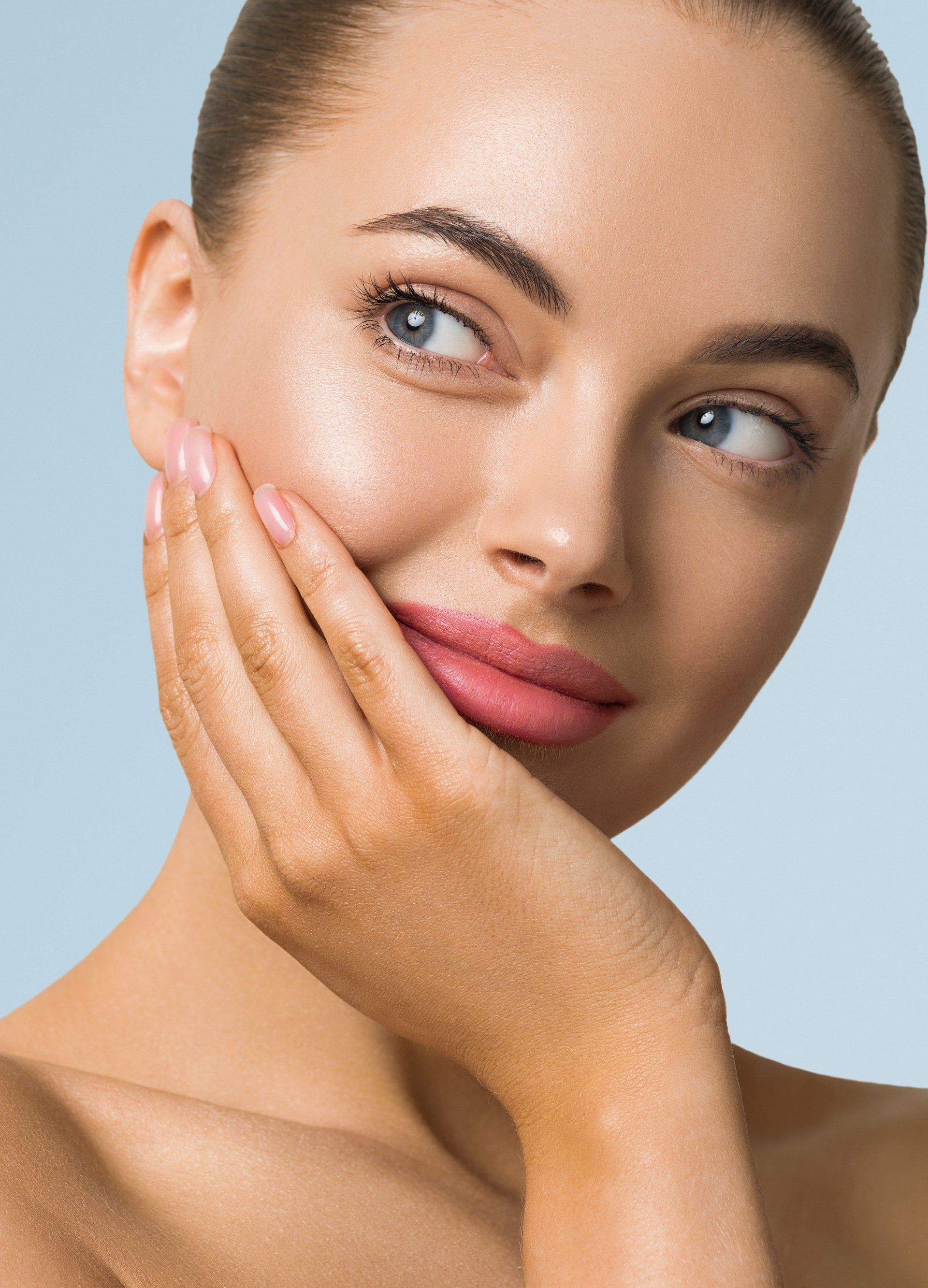 A woman is touching her face with her hand and smiling.
