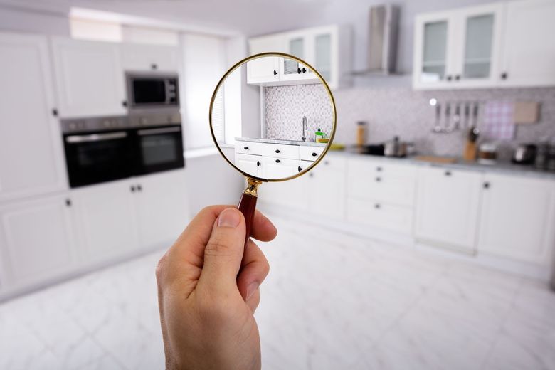 A person is holding a magnifying glass in front of a kitchen.