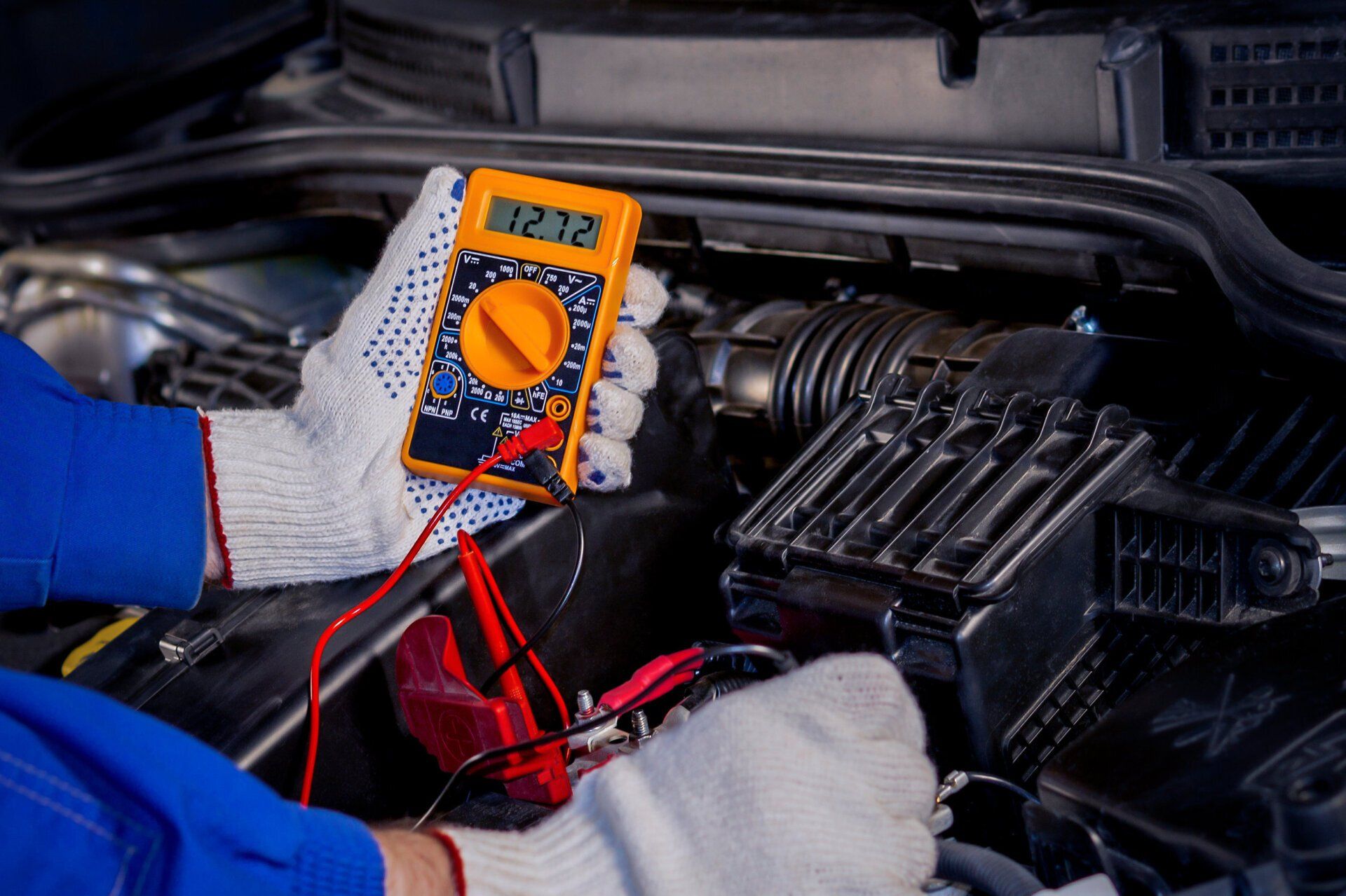 Mechanic testing car engine with a multimeter under the hood