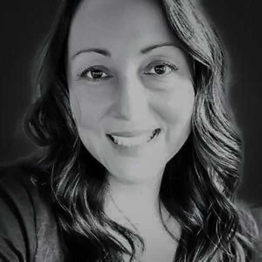 Smiling woman with long, wavy hair; close-up in grayscale.