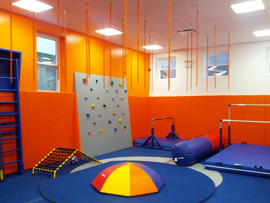 A gym with a climbing wall and a ball in the middle