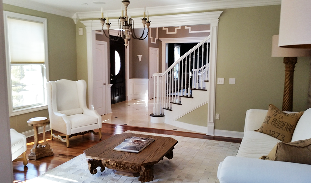 A living room with a couch , chairs , coffee table and stairs.