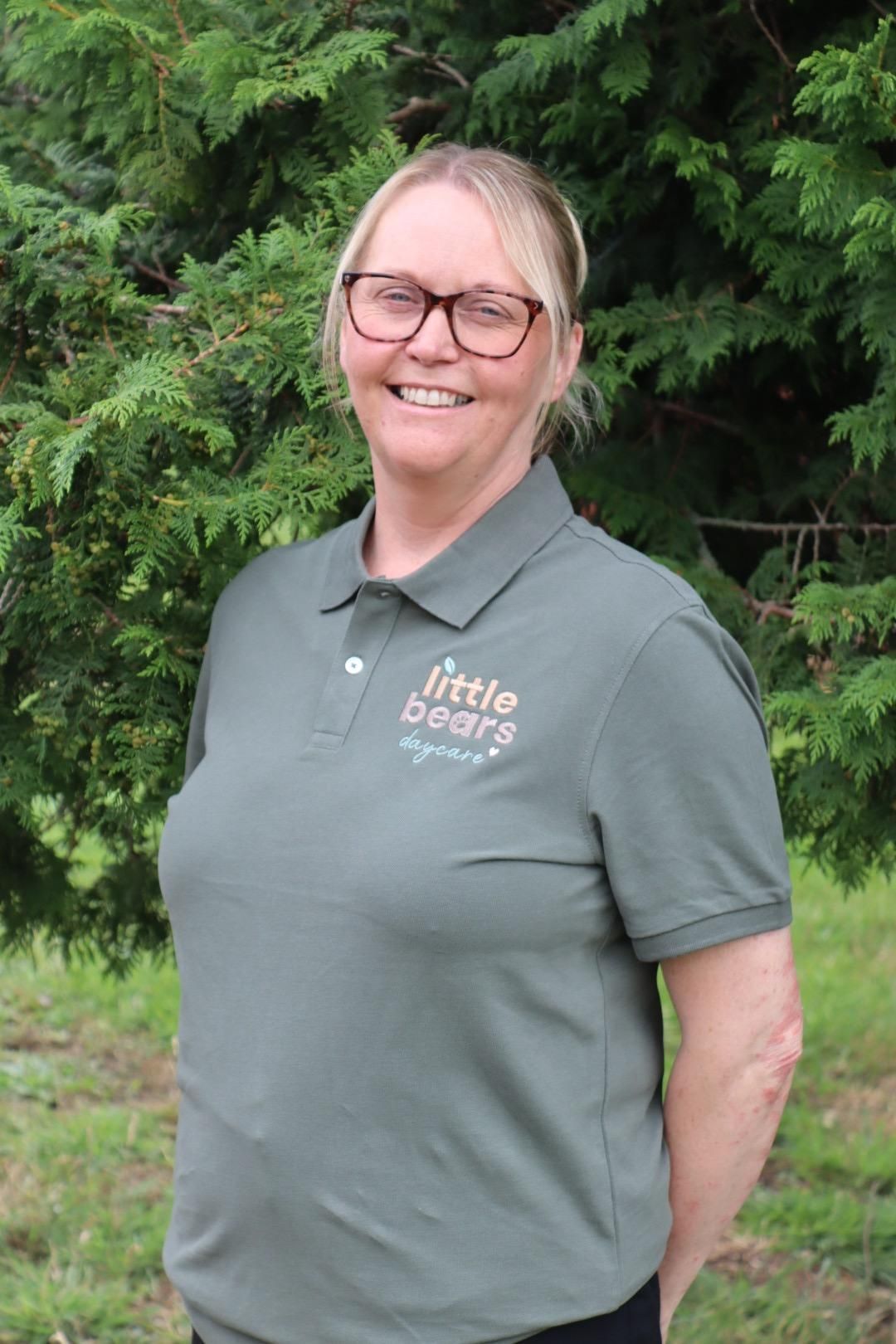 Woman smiling, wearing glasses and green polo shirt with 
