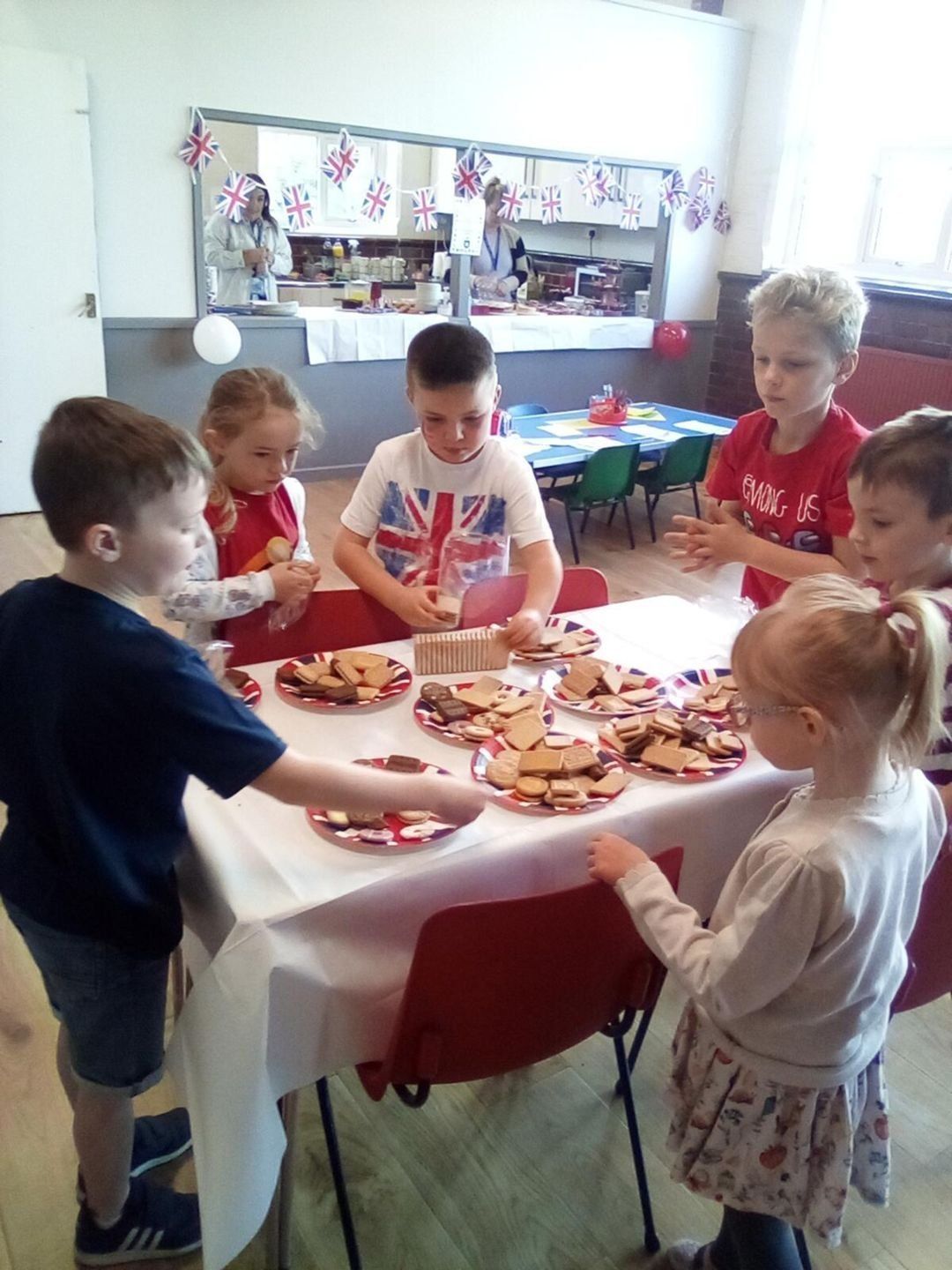 Children around a table with treats, decorated for an event.