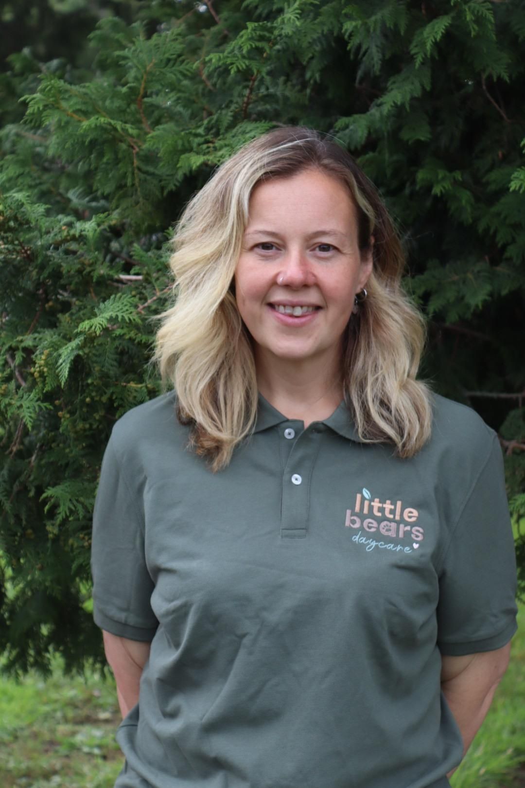 Woman with blonde hair wearing a green polo shirt with 