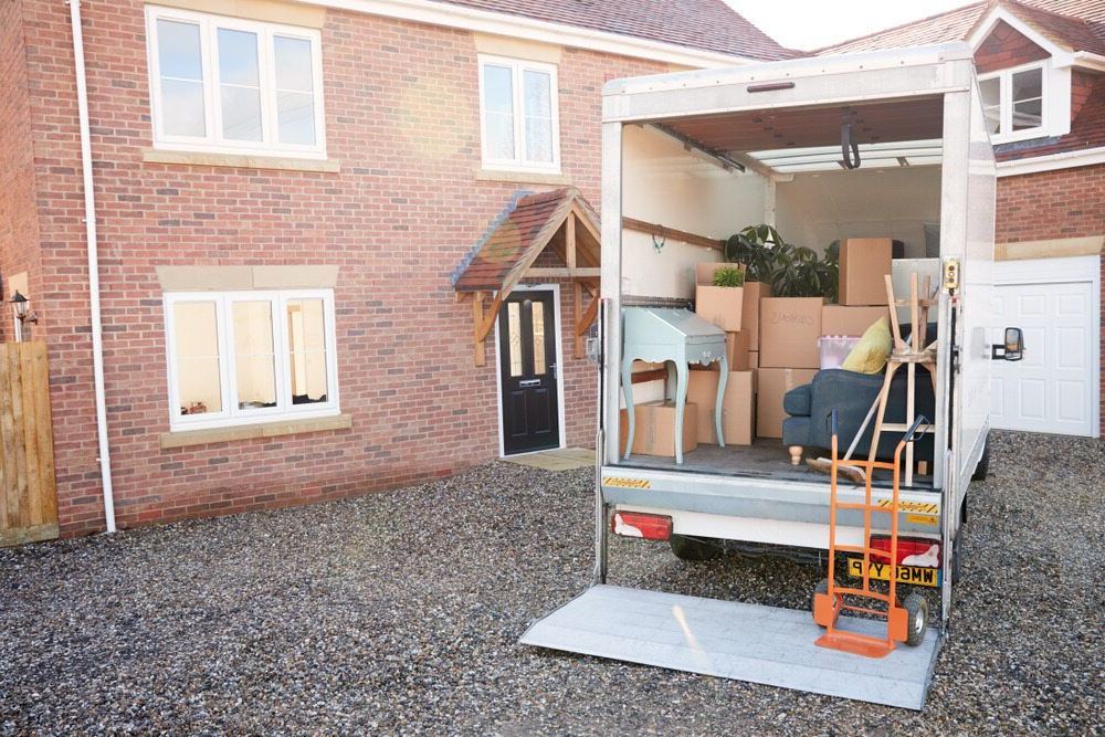 A Moving Truck is Parked in Front of a Brick House — Johns Removals Newcastle In Cessnock, NSW