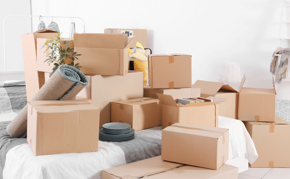 A Pile of Cardboard Boxes Sitting on Top of a Bed — Johns Removals Newcastle In Newcastle, NSW