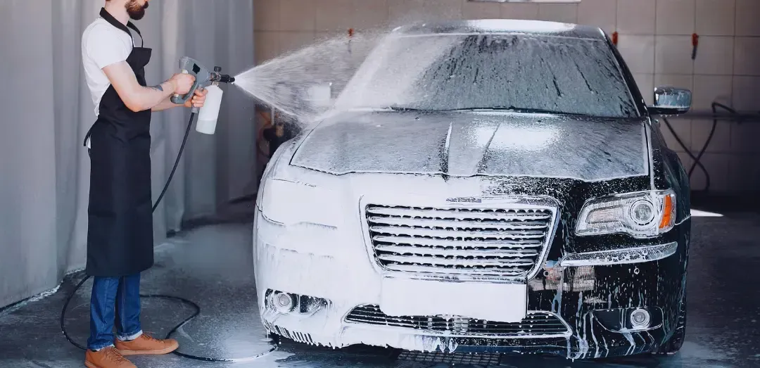 A man is washing a car with foam in a car wash.