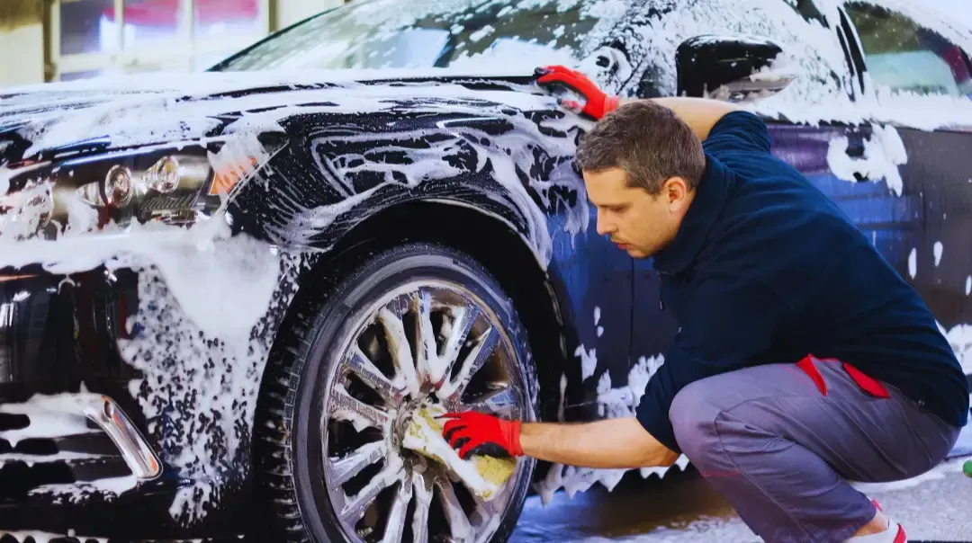 A man is washing a car with soap and water.