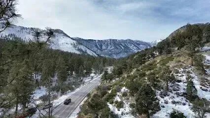 Mobile Detailing-Snowy mountain valley with a road winding through it. Evergreen trees line the road.