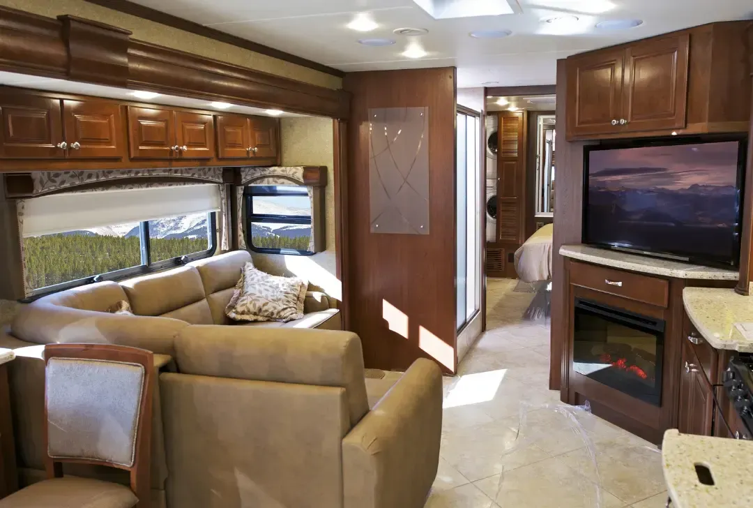 A living room in a rv with a couch , television and fireplace.