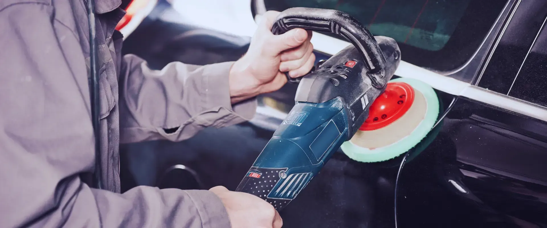 A man is polishing a car with a machine.