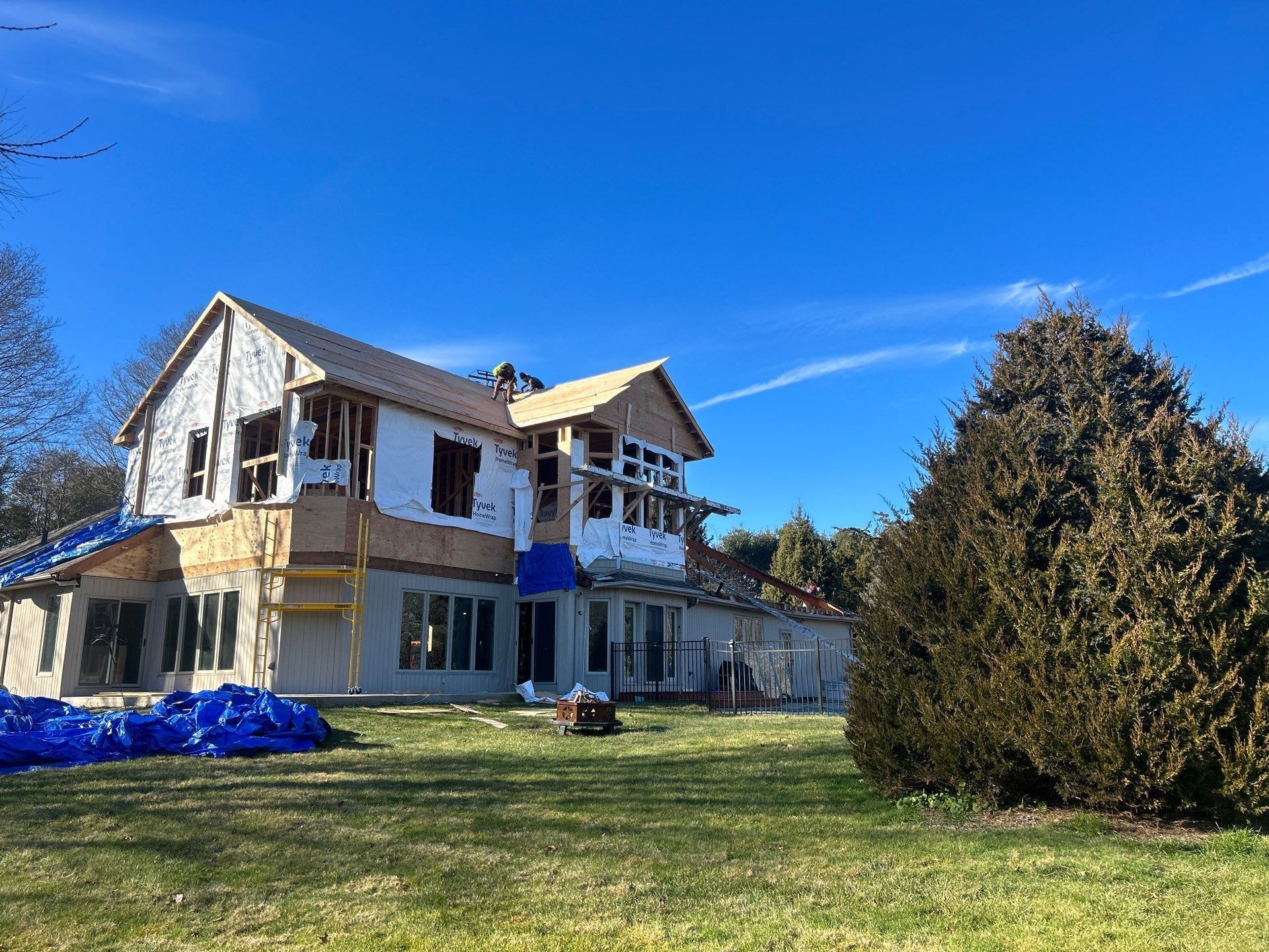 A large house is being built in the middle of a grassy field.